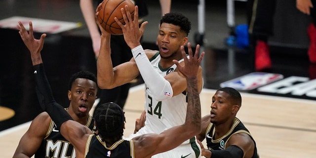 Milwaukee Bucks' Giannis Antetokounmpo (34) passes the ball as Atlanta Hawks' Cam Reddish (22) defends during the first half of Game 4 of the NBA basketball Eastern Conference finals Tuesday, June 29, 2021, in Atlanta. (AP Photo/Brynn Anderson)