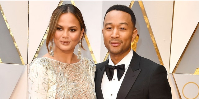 John Legend told TMZ cameras on Tuesday that his wife is ‘doing great’ amid the cyberbullying scandal.