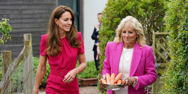 Britain's Kate, Duchess of Cambridge, left, and US First Lady Jill Biden, carrying carrots for the school rabbit, Storm, during a visit to Connor Downs Academy in Hayle, West Cornwall, during the G7 summit in England, Friday, June 11, 2021. (Aaron Chown/Pool photo via AP)