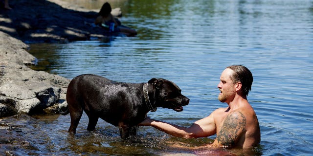 Justin Swanner and his dog Havoc swim in the Clackamas River to escape from the heat during a record setting heat wave in Oregon City, Ore., Sunday, June 27, 2021. Yesterday set a record high for the day with more records expected today.