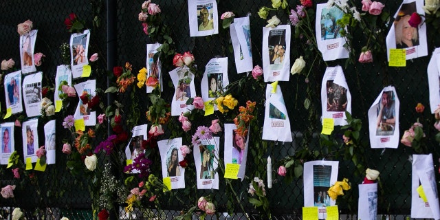 Photos of missing residents are posted at a makeshift memorial at the site of a collapsed building in Surfside, Florida, north of Miami Beach,on June 26, 2021. - An engineer warned of "major structural damage" at a Florida apartment building three years before it partially collapsed, a report said June 26, as rescuers raced to find 159 people still unaccounted for in the mountain of debris. Four people have been confirmed dead after the 12-story oceanfront building in Surfside pancaked as residents slept inside in the early hours of June 24. (Photo by Andrea SARCOS / AFP) (Photo by ANDREA SARCOS/AFP via Getty Images)