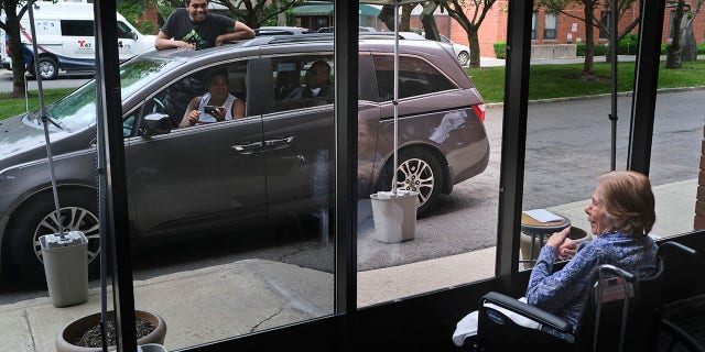 June 11, 2020: In this file photo, Gloria DeSoto, 92, right, visits with her family, in their car, from a window of the Hebrew Home at Riverdale, where she lives, in New York.