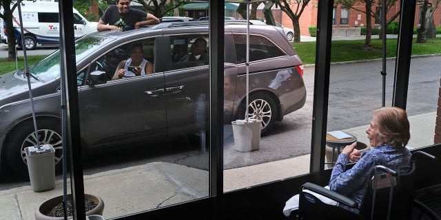 June 11, 2020: In this file photo, Gloria DeSoto, 92, right, visits with her family, in their car, from a window of the Hebrew Home at Riverdale, where she lives, in New York. 