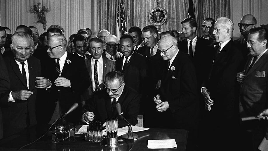 Johnson signing Civil Rights Act with MLK Jr. photographed