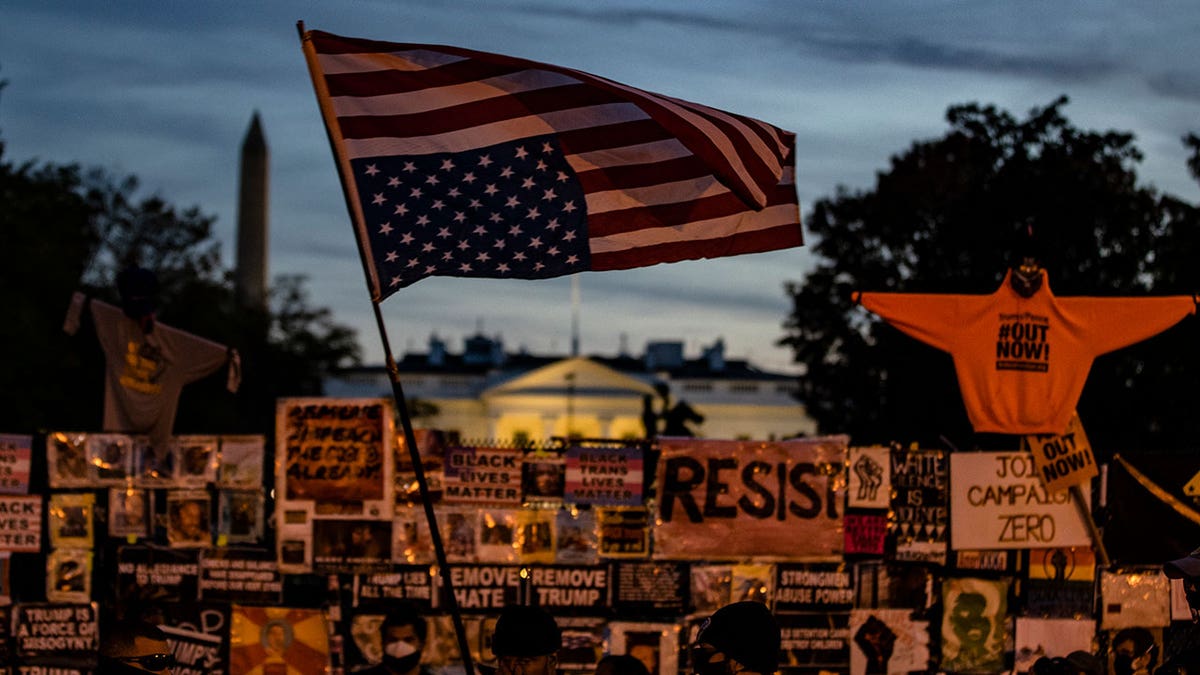 WASHINGTON, DC - NOVEMBER 05: A woman waves an upside down American flag as people gather at Black Lives Matter Plaza as they wait for the results of the presidential election between incumbent President Donald Trump and former Vice President Joe Biden in front of the White House on November 5, 2020 in Washington, DC. Biden currently has the lead over Trump with 253-214 electoral college votes but four states - North Carolina, Georgia, Pennsylvania, and Nevada - have yet to be called for either candidate. (Photo by Samuel Corum/Getty Images)