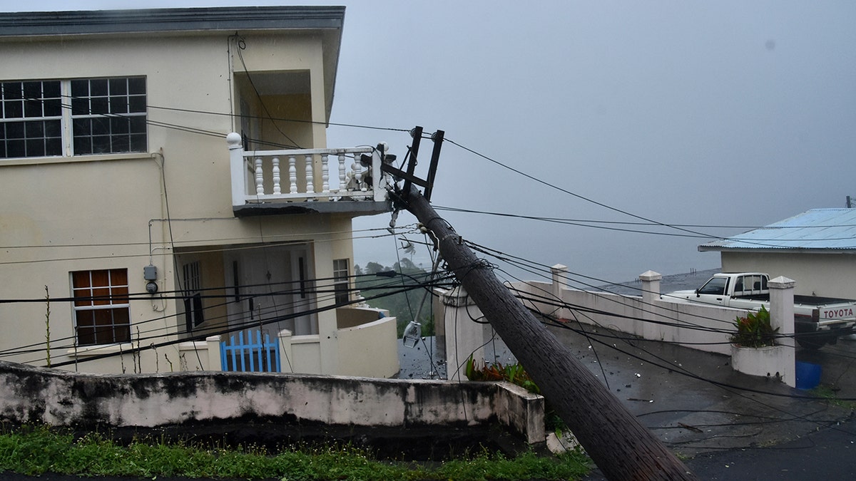 An electrical pole felled by Hurricane Elsa leans on the edge of a residential balcony, in Cedars, St. Vincent, Friday, July 2, 2021. (Associated Press)