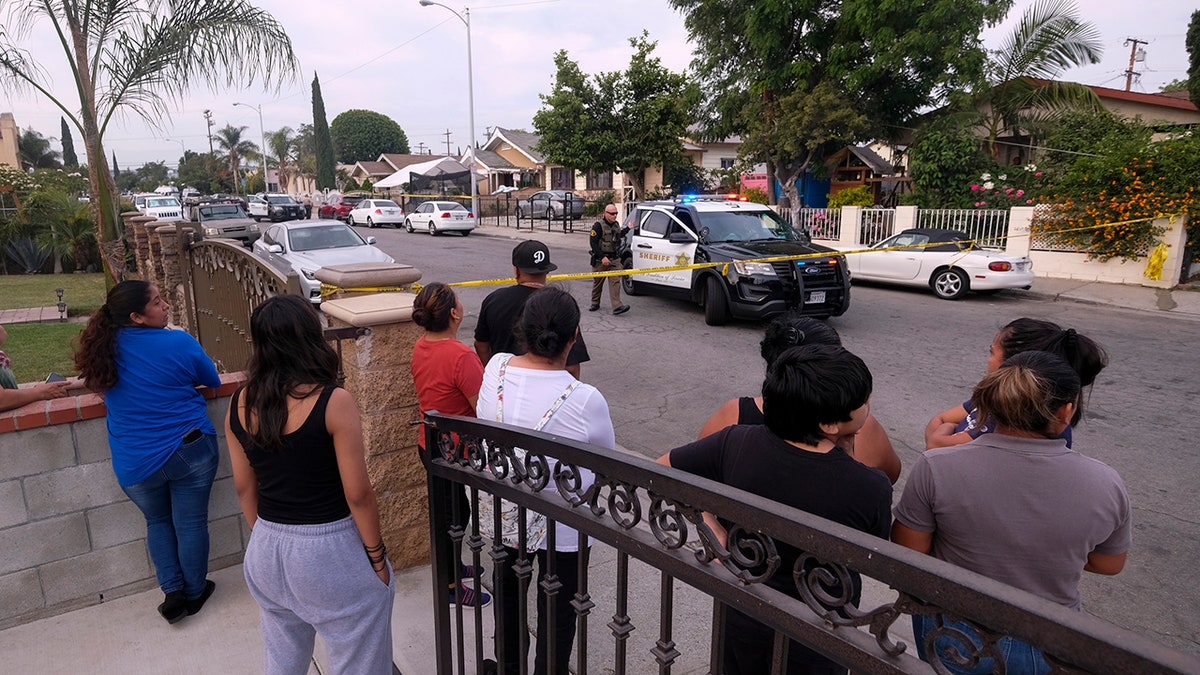 Residents watch as authorities work at the scene after three young children were found dead in a bedroom at a residence in East Los Angeles, Monday, June 28, 2021. (Associated Press)