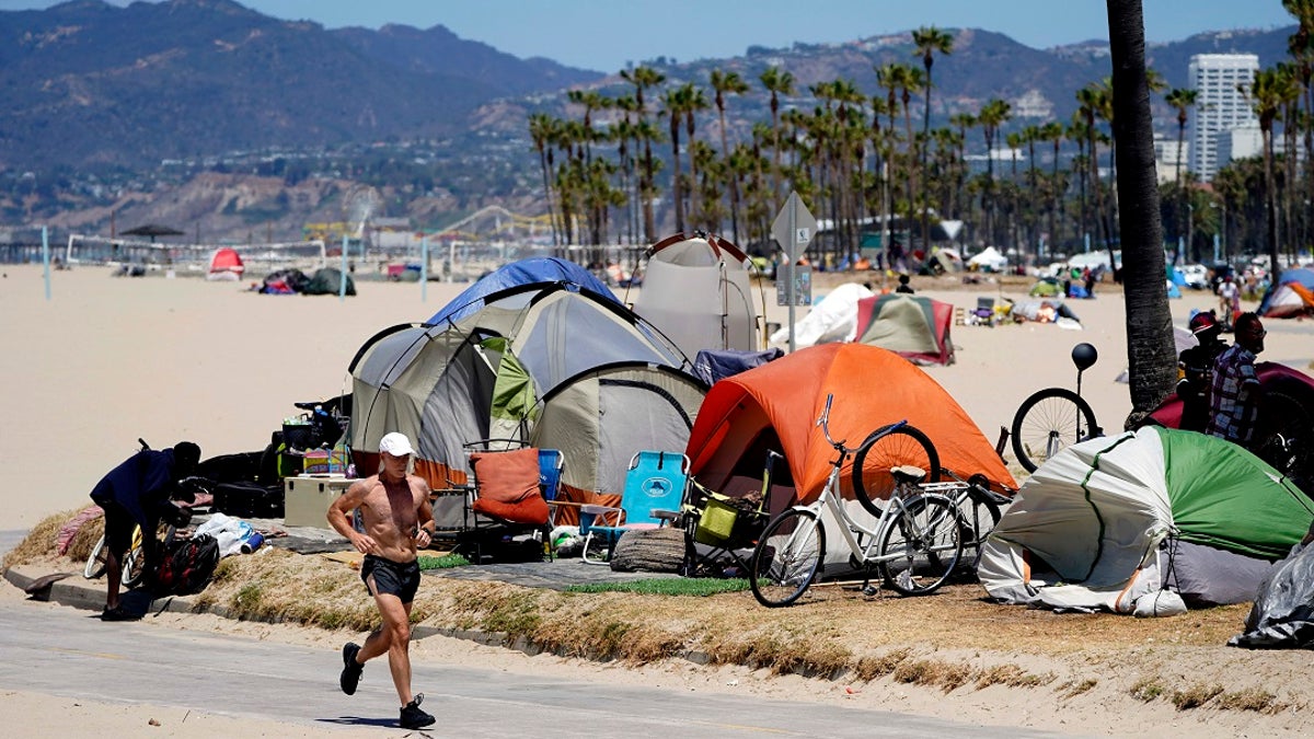 A jogger walks past a homeless encampment in the Venice Beach section of Los Angeles.