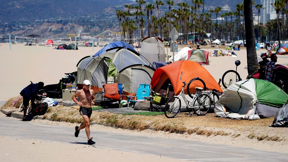 A jogger walks past a homeless encampment in the Venice Beach section of Los Angeles.