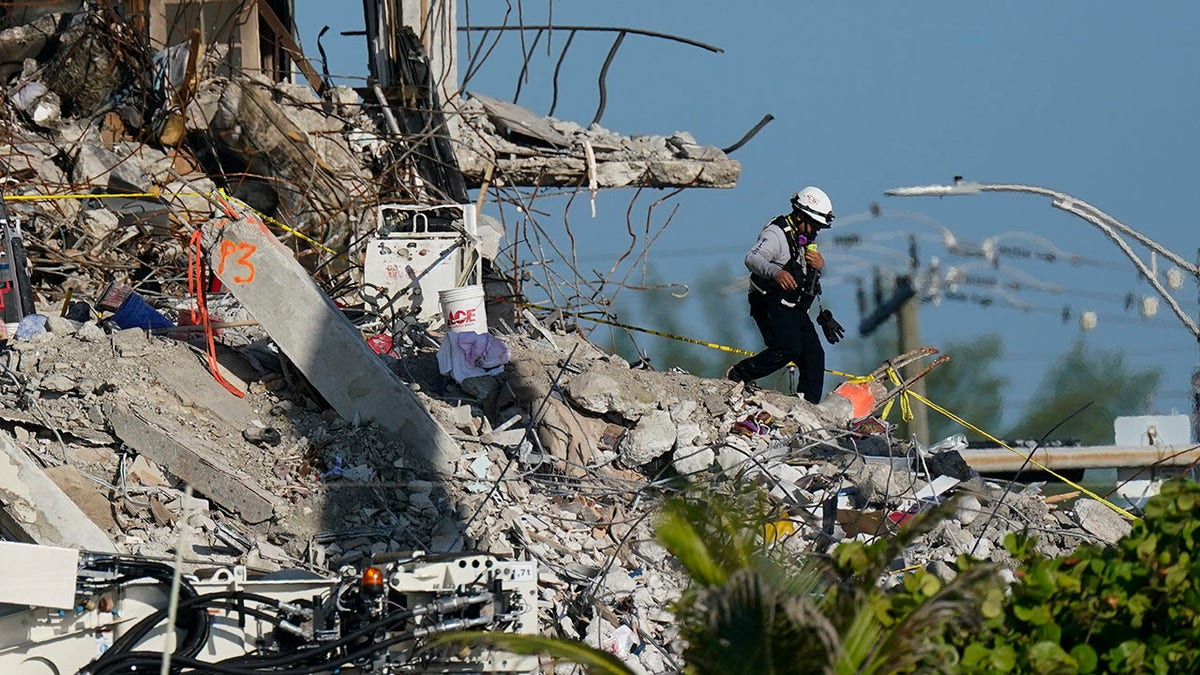 A man descends from the rubble pile, as members of the search and rescue personnel work atop the debris at the Champlain Towers South condo building on Friday. (AP)