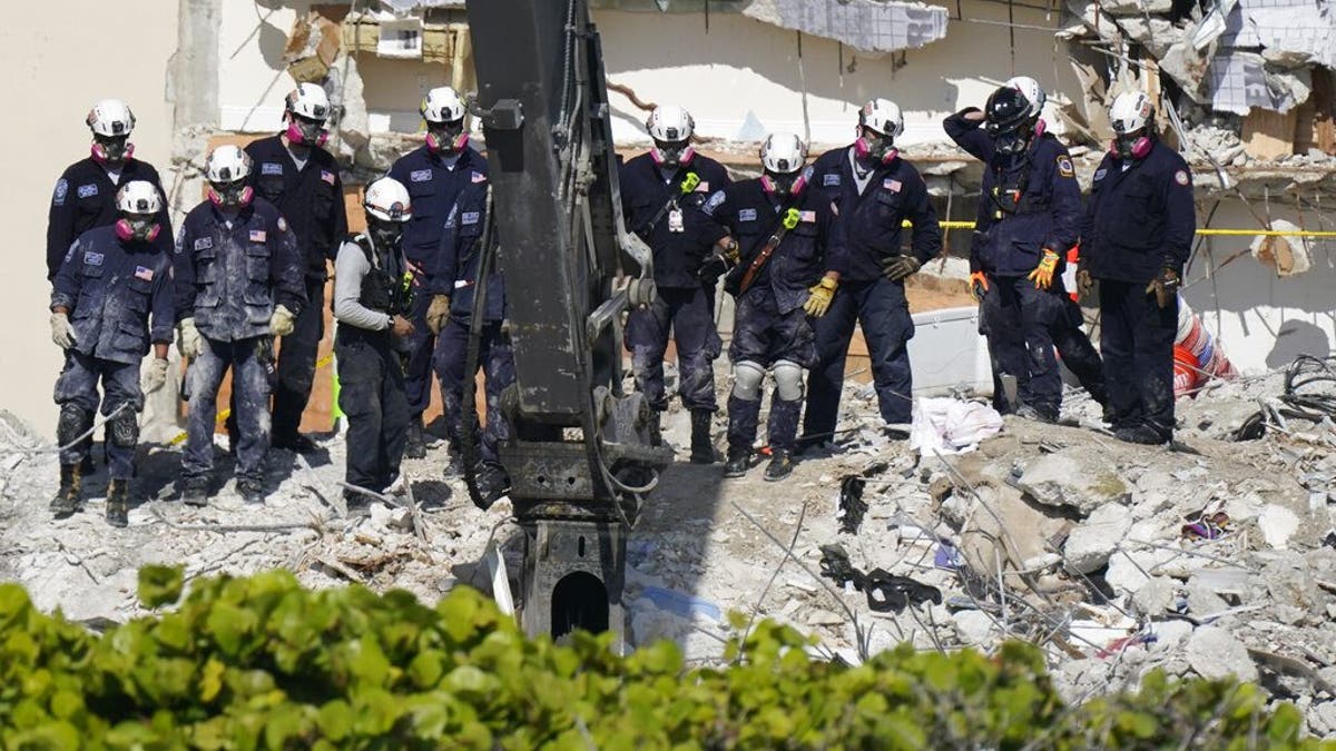 Search and rescue personnel work alongside heavy machinery atop the rubble at the Champlain Towers South condo building, where scores of people remain missing more than a week after it partially collapsed, Friday, July 2, 2021, in Surfside, Fla. Rescue efforts resumed Thursday evening after being halted for most of the day over concerns about the stability of the remaining structure.(AP Photo/Mark Humphrey)