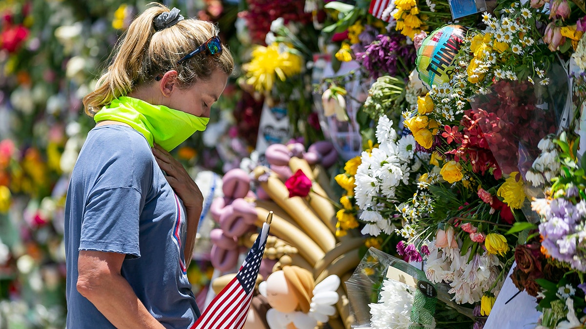 Miami Beach resident Tracey Lynne visits a makeshift memorial near the site of the collapsed Champlain Towers South Condo in Surfside, Florida, on Saturday, July 3, 2021. (Associated Press)