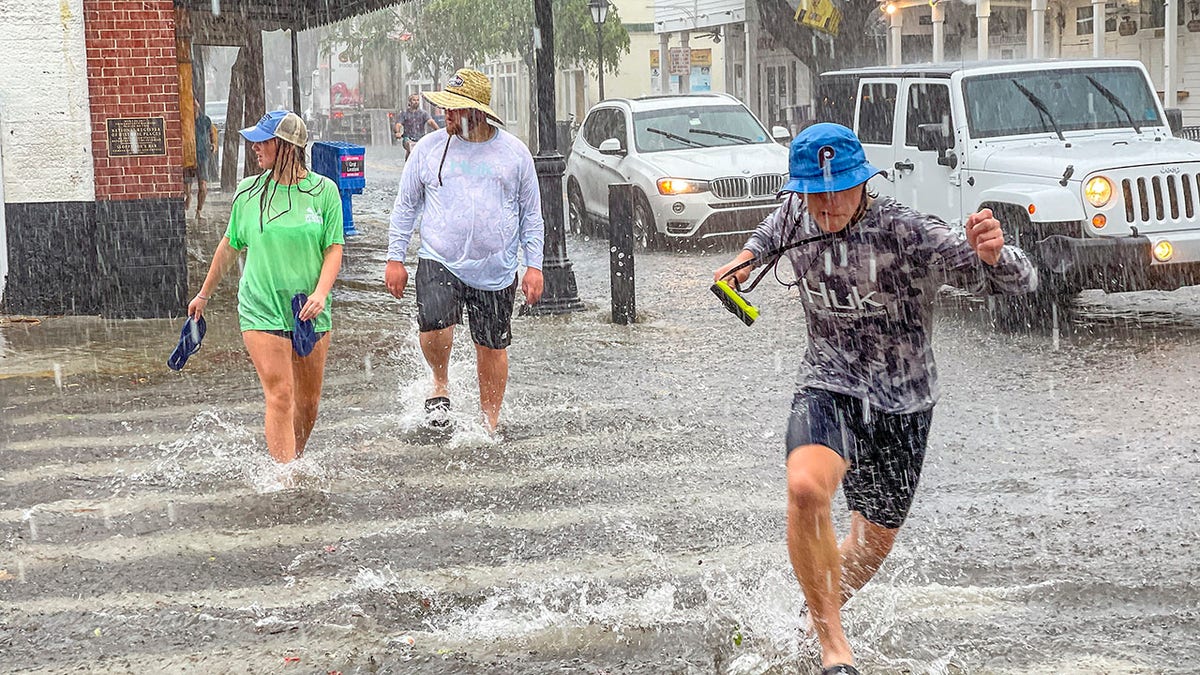 Pedestrians dash across the intersection of Greene and Duval streets as heavy winds and rain associated with Tropical Storm Elsa passes Key West, Fla., on Tuesday, July 6, 2021. (Rob O'Neal/The Key West Citizen via AP)