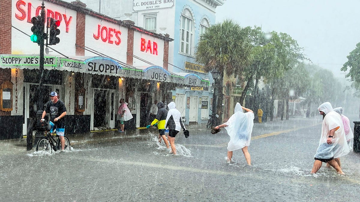 Determined visitors head for Sloppy Joe's Bar while crossing a flooded Duval Street as heavy winds and rain pass over Key West, Fla., Tuesday, July 6, 2021. (Rob O'Neal/The Key West Citizen via AP)