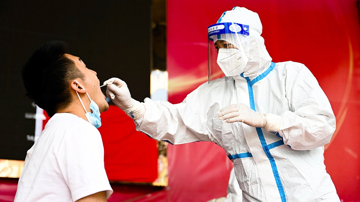 In this photo released by Xinhua News Agency, a medical worker collects a swab sample for nucleic acid test in Ruili City of southwest China's Yunnan Province, on July 5, 2021. (Wang Guansen/Xinhua via AP)