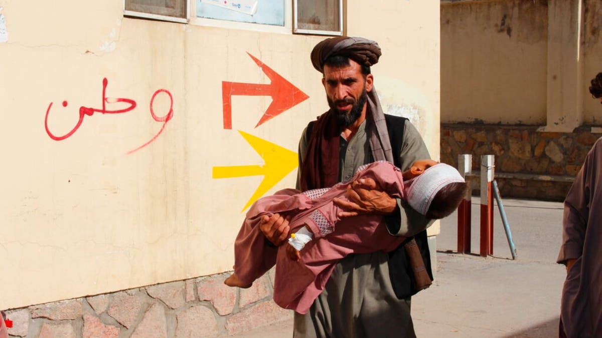 An Afghan civilian carry a wounded child to the hospital after he was injured during fighting between Taliban and government in Badghis province, northwest of Afghanistan, Wednesday, July, 7 2021.