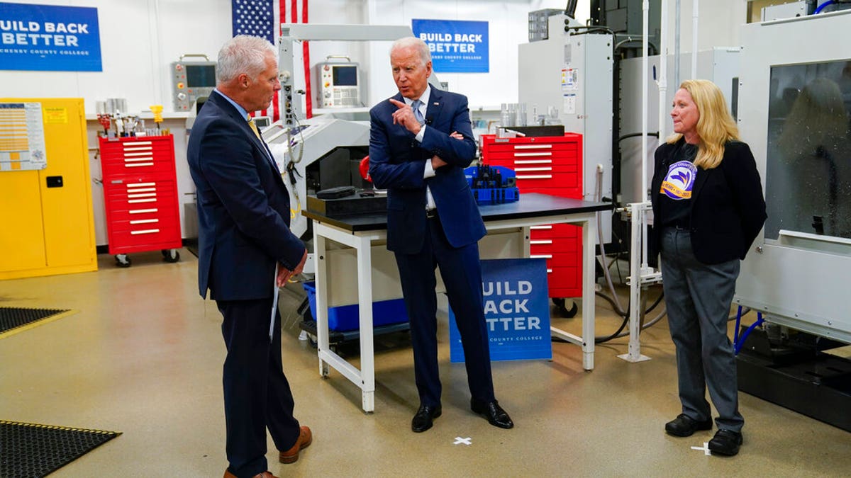 President of McHenry County College Clint Gabbard, listens as President Joe Biden speaks as he tours a manufacturing lab at McHenry County College during an event highlighting infrastructure spending, Wednesday, July 7, 2021, in Crystal Lake, Ill. (AP Photo/Evan Vucci)