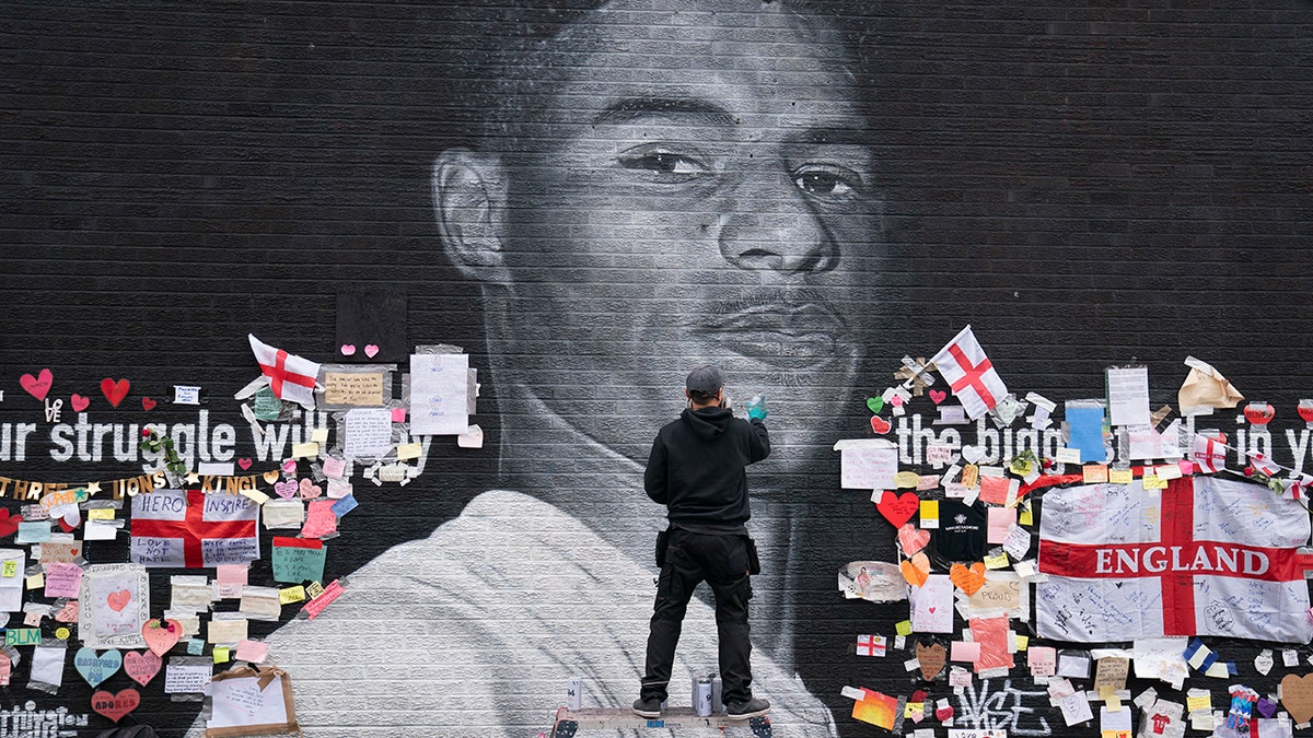 Street artist Akse P19 repairs the mural of Manchester United striker Marcus Rashford in Manchester on July 13, 2021. The mural was defaced after England lost the Euro 2020 soccer championship to Italy. (AP Photo/Jon Super)
