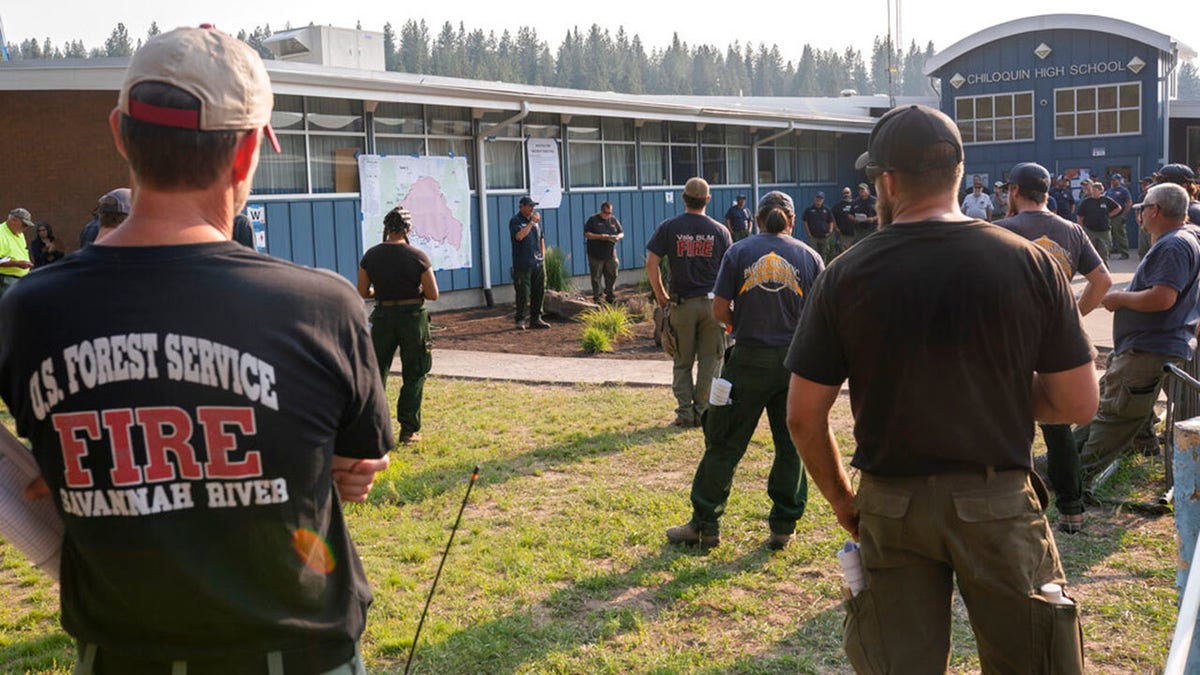 Firefighters from Oregon and other nationwide agencies meet at Chiloquin High School before heading toward the Bootleg Fire, Tuesday, July 13, 2021, in Chiloquin, Ore. (AP Photo/Nathan Howard)