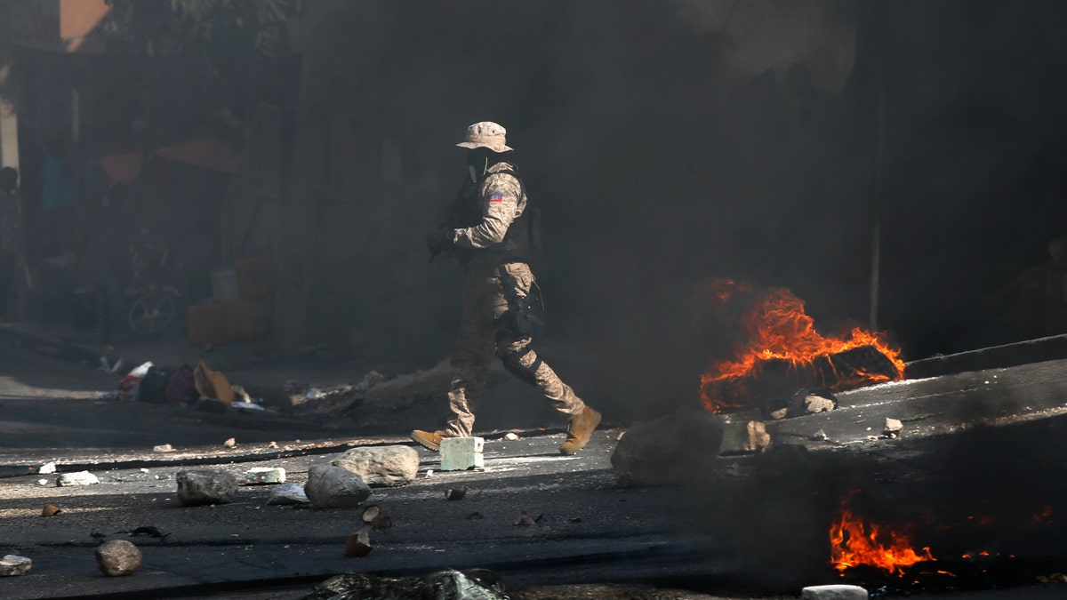 Police work to clear a road blocked by rocks and tires set fire by protesters upset with growing violence in the Lalue neighborhood of Port-au-Prince, Haiti, Wednesday, July 14, 2021. Haitian President Jovenel Moise was assassinated on July 7. (AP Photo/Fernando Llano)