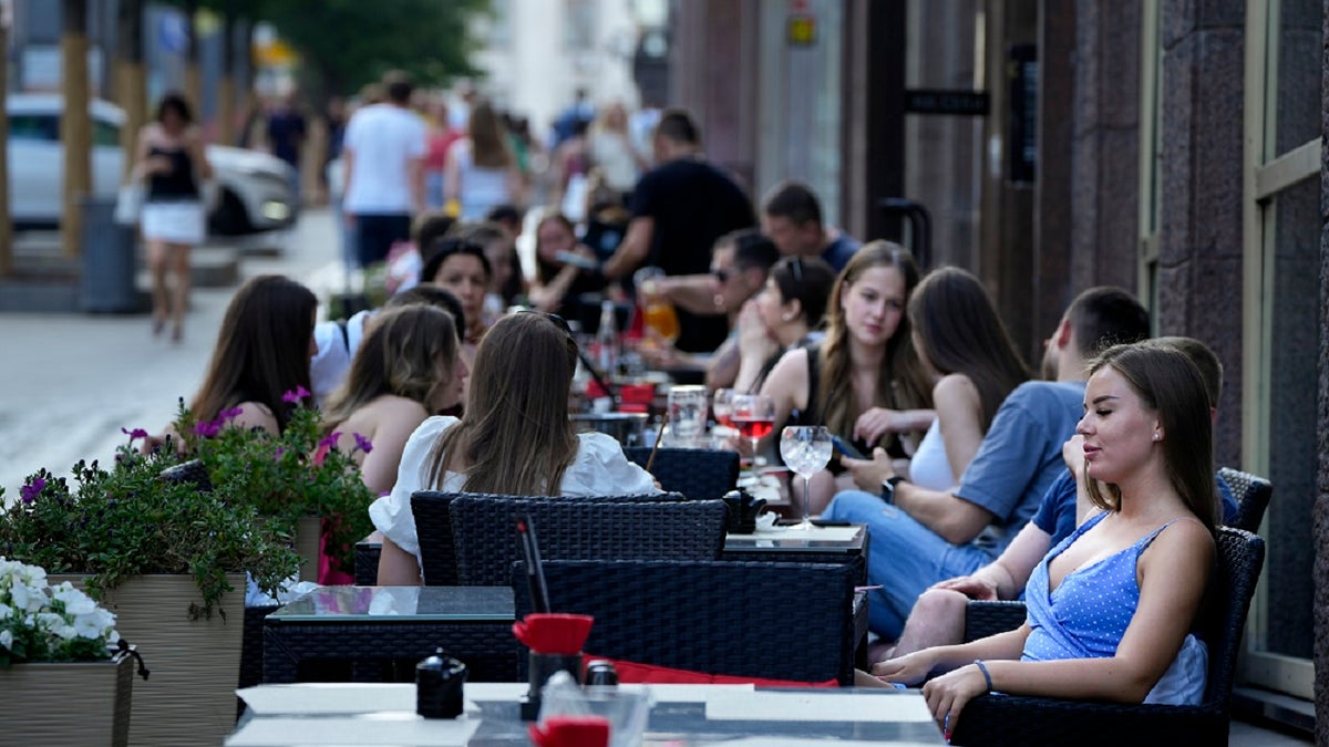 People relax after a hot day at an outdoor terrace of a restaurant in Moscow, Russia, Wednesday, July 14, 2021. (AP)