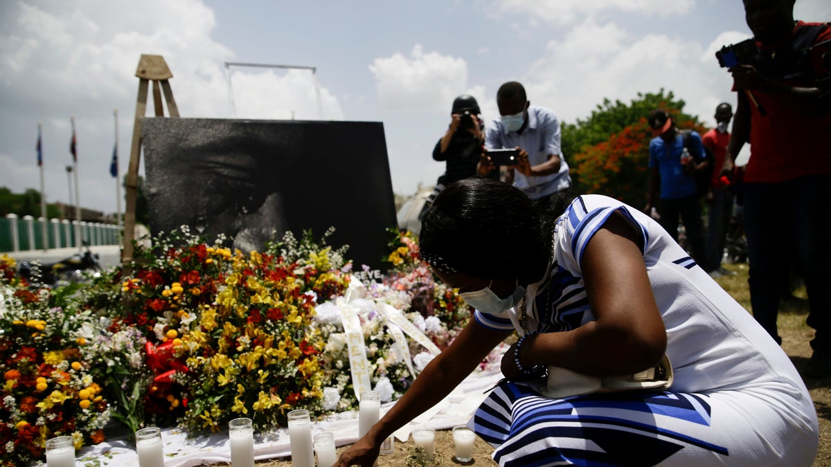 A woman lights a candle at a memorial outside the Presidential Palace in memory of slain President Jovenel Moise in Port-au-Prince, Haiti, Wednesday, July 14, 2021, a week after Moise was assassinated in his home. (AP Photo/Joseph Odelyn)