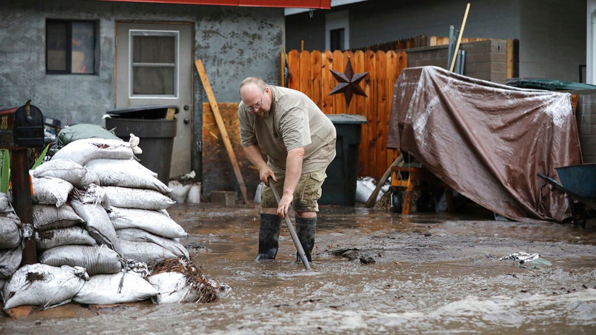 A resident shovels back floodwater as monsoon rains fell on the Museum Fire burn area causing flooding from the Paradise Wash in east Flagstaff, Ariz. on Wednesday, July 14, 2021. The threat of flash flooding will remain through next week, the National Weather Service said, though the coverage will be more scattered than widespread. (Jake Bacon/Arizona Daily Sun via AP)