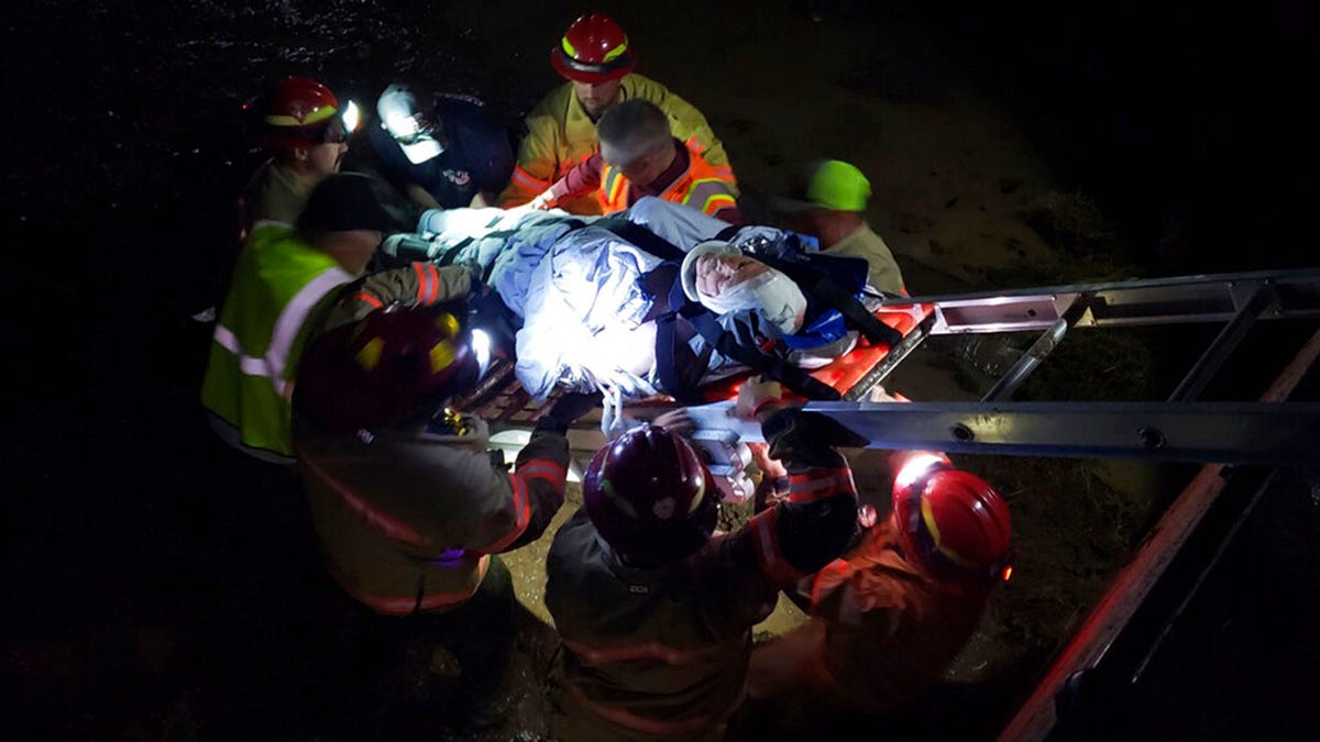 In this photo provided by the Iron County Sheriff's Department, emergency personnel remove an injured train worker from the scene of a derailment near Lund, Utah, on Thursday, July 15, 2021. Three workers on a freight train were injured when it derailed while crossing tracks covered with water in a remote part of southern Utah Thursday night, authorities said. The train, which had nearly 100 cars, tipped on its side after derailing near Lund, about 85 miles from the Nevada border. (Iron County Sheriff's Dept. via AP)