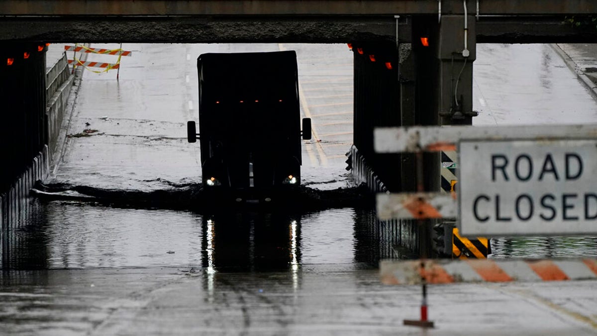A semi-trailer drives through a flooded street, Friday, July 16, 2021, in Dearborn, Mich. Detroit area residents are still drying out their basements from the flooding last month, but now more flooding is on the horizon as a heavy rain front moves through southern Michigan. (AP Photo/Carlos Osorio)