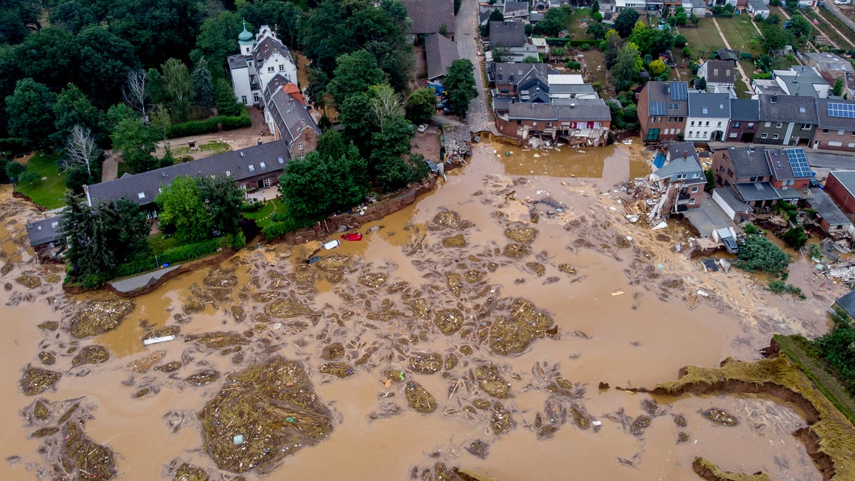 The damaged castle, left, is seen in Erftstadt-Blessem, Germany, Saturday, July 17, 2021. Due to strong rain falls the small Erft river went over the banks causing massive damages. (AP Photo/Michael Probst)