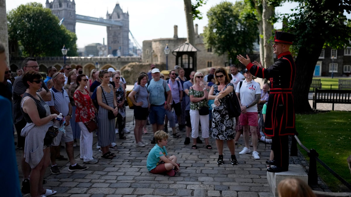 On what some have called "Freedom Day", marking the end of coronavirus restrictions in England, visitors listen as Yeoman Warder Barney Chandler leading the first tour of the Tower of London in 16 months since the start of the coronavirus outbreak, in London, Monday, July 19, 2021. Beginning Monday, face masks will no longer be legally required and with social distancing rules shelved, but mask rules will remain for passengers on the London transport network.  (AP Photo/Matt Dunham)
