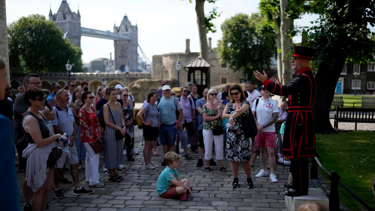 On what some have called "Freedom Day", marking the end of coronavirus restrictions in England, visitors listen as Yeoman Warder Barney Chandler leading the first tour of the Tower of London in 16 months since the start of the coronavirus outbreak, in London, Monday, July 19, 2021. Beginning Monday, face masks will no longer be legally required and with social distancing rules shelved, but mask rules will remain for passengers on the London transport network. (AP Photo/Matt Dunham)