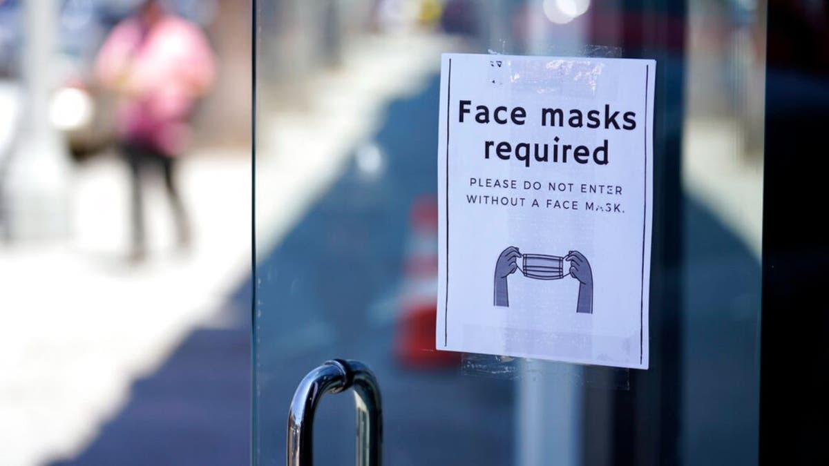 A sign advises shoppers to wear masks outside of a story Monday, July 19, 2021, in the Fairfax district of Los Angeles. Los Angeles County has reinstated an indoor mask mandate due to rising COVID-19 cases.