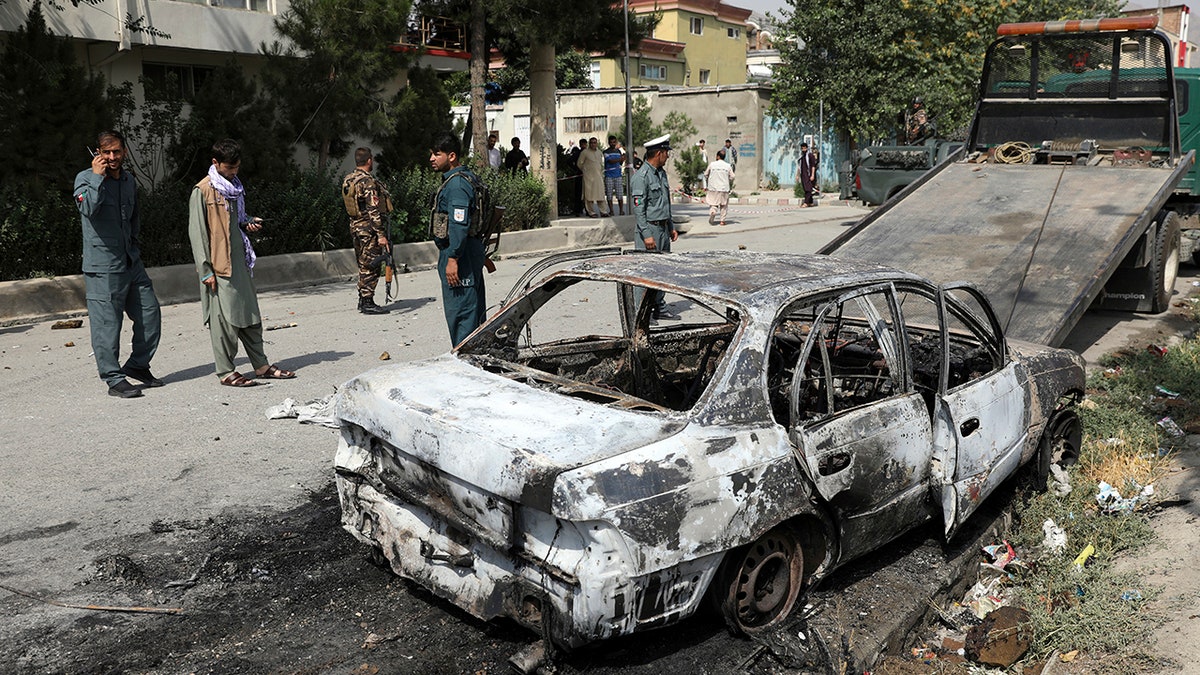 Security personnel inspect a damaged vehicle where rockets were fired from in Kabul, Afghanistan, Tuesday, July 20, 2021. (AP Photo/Rahmat Gul)