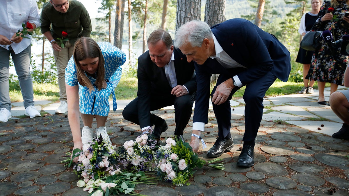 Leader of AUF youth political league in Norway, Astrid Hoem, Prime Minister of Sweden Stefan Lofven and leader of the Norwegian Labor Party Jonas Gahr Store, lay flower tributes at the memorial on Utoya island Wednesday, July 21, 2021. (Beate Oma Dahle / NTB via AP)