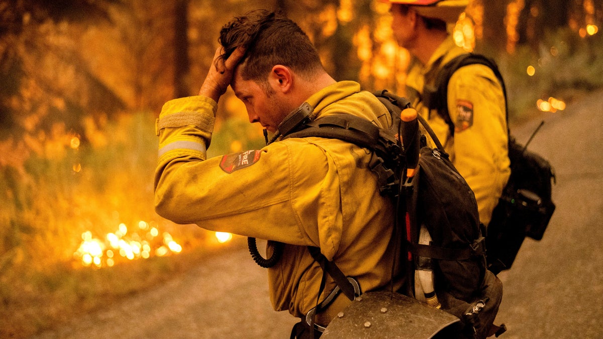 Firefighter Jesse Forbes rubs his head while battling the Dixie Fire near Prattville in Plumas County, Calif., on Friday, July 23, 2021. (AP Photo/Noah Berger)