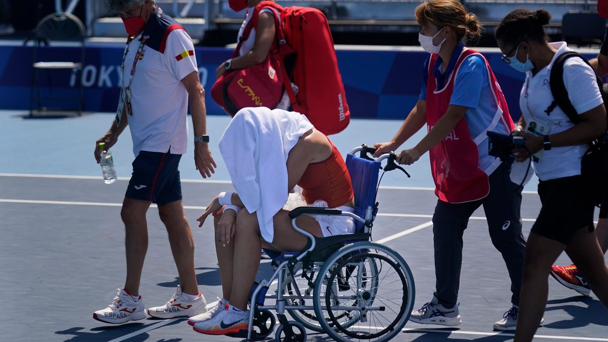 Paula Badosa, of Spain, is helped off the court 