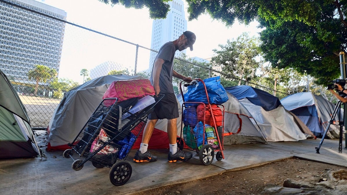 A homeless man in California moves his belongings from a street near Los Angeles City Hall