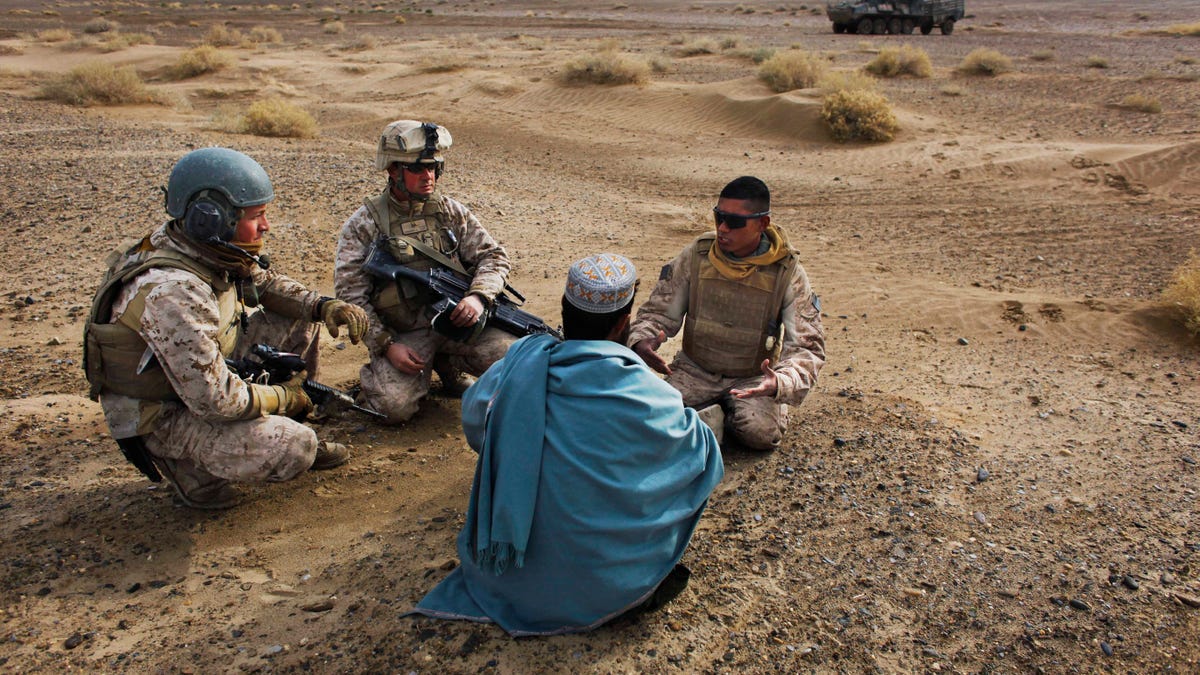 In this Friday, Dec. 11, 2009, file photo, United States Marine Sgt. Isaac Tate, left, and Cpl. Aleksander Aleksandrov, center, interview a local Afghan man with the help of a translator from the 2nd MEB, 4th Light Armored Reconnaissance Battalion on a patrol in the volatile Helmand province of southern Afghanistan. More than 200 Afghans were due to land Friday in the United States in the first of several planned evacuation flights for former translators and others as the U.S. ends its nearly 20-year war in Afghanistan. (AP Photo/Kevin Frayer, File)