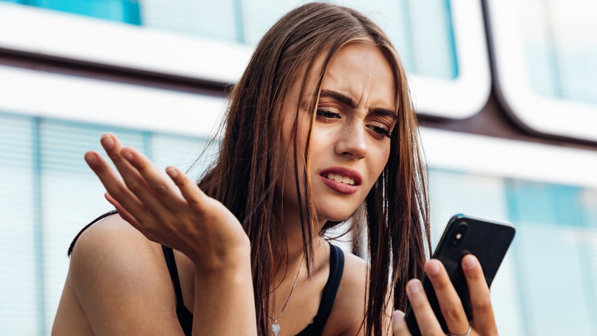 Woman looking at phone while frustrated