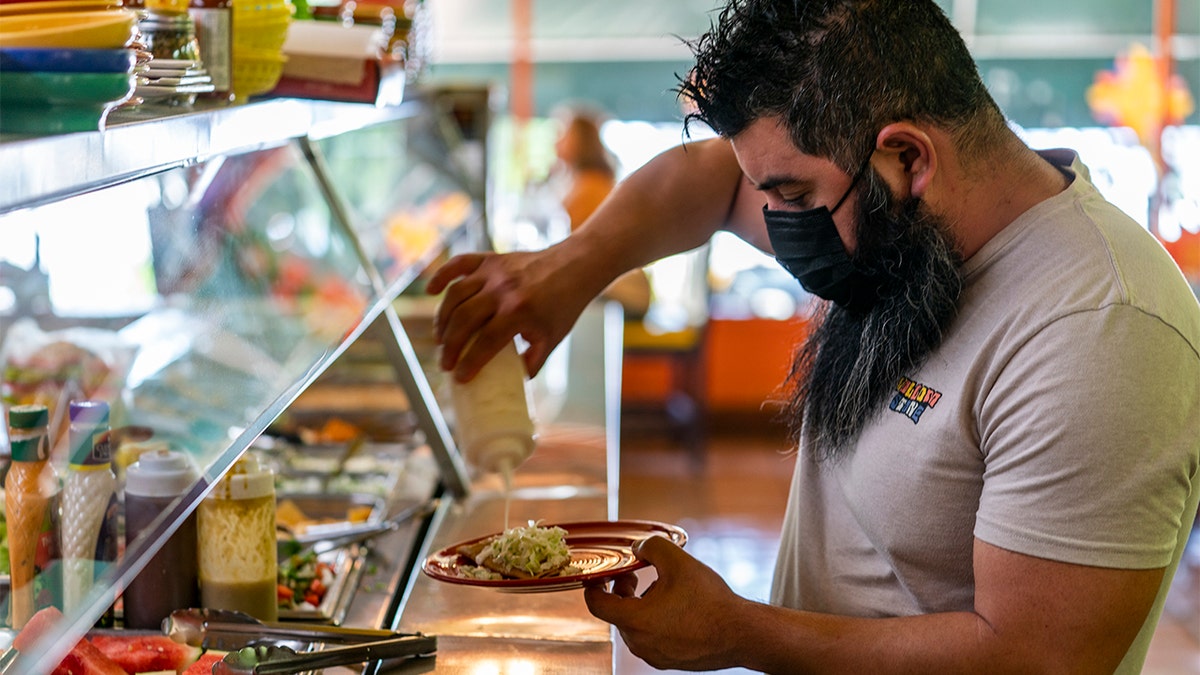 Gustavo Arellano, 36, who is vaccinated, wears a  face mask as he fixes himself a plate at Taqueria El Sol buffet in Los Angeles' Boyle Heights neighborhood in Los Angeles, Thursday, July 22, 2021. 