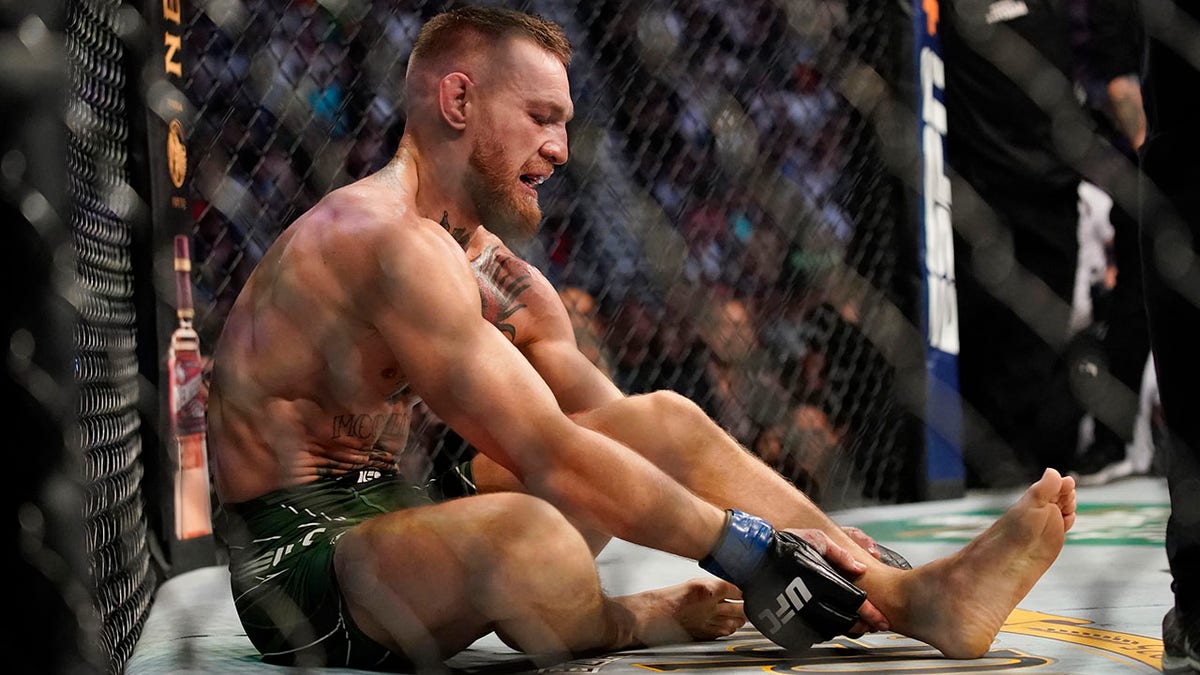 Conor McGregor holds his right ankle while fighting Dustin Poirier during a UFC 264 lightweight mixed martial arts bout Saturday, July 10, 2021, in Las Vegas. (AP Photo/John Locher)