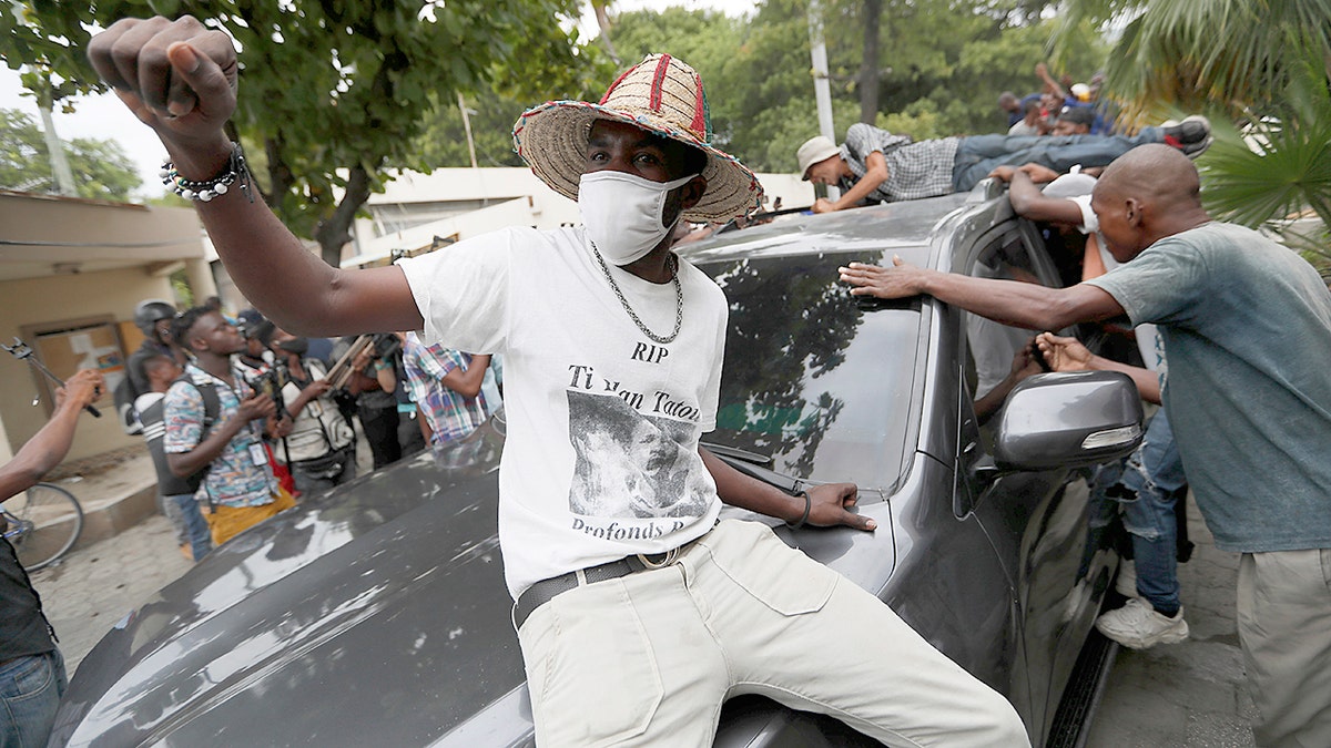 Supporters of former Senator Steven Benoit shout outside the courthouse as he departs after being called in for questioning, in Port-au-Prince, Monday, July 12, 2021. Prosecutors have requested that high-profile politicians like Benoit meet officials for questioning as part of the investigation into the assassination of President Jovenel Moise. (AP Photo/Fernando Llano)