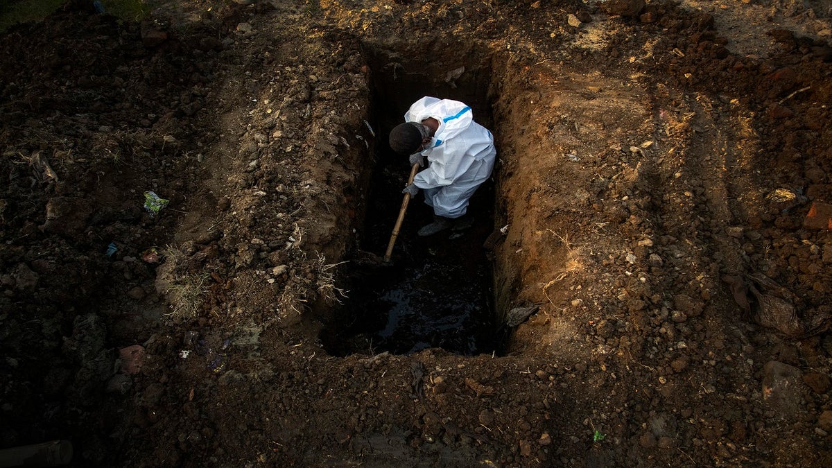 A man in protective suit digs earth to bury the body of a person who died of COVID-19 in Gauhati, India, on April 25. 