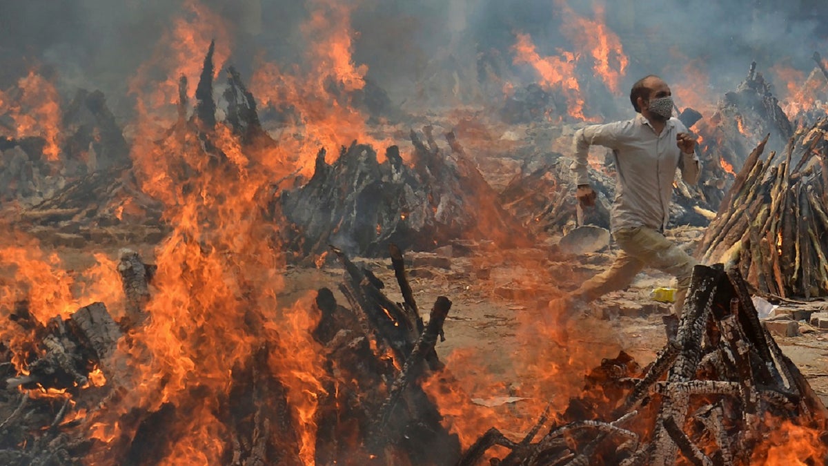 A man runs to escape heat emitting from the multiple funeral pyres of COVID-19 victims at a crematorium in the outskirts of New Delhi, India, on April 29.