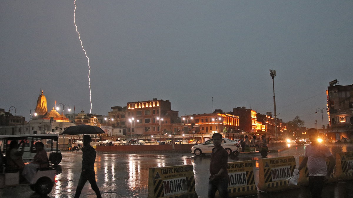 Commuters crosses a road as it rains during a lightning strike in the sky in Jaipur, Rajasthan, India, July 11,2021.