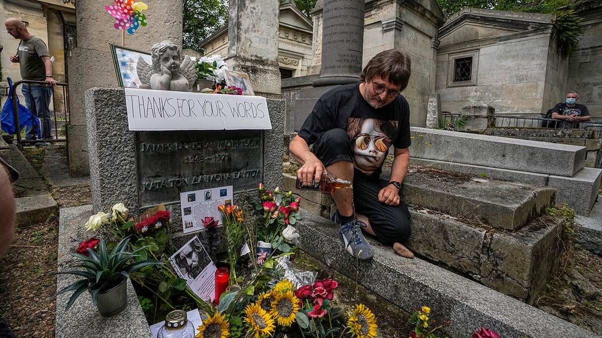Torsten Marquardt of Germany pours some whiskey on the tomb of rock singer Jim Morrison at the Pere-Lachaise cemetery in Paris, Saturday, July 3, 2021. (Associated Press)