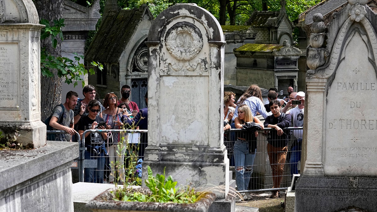 Fans gather at the tomb of rock singer Jim Morrison at the Pere-Lachaise cemetery in Paris, Saturday, July 3, 2021. (Associated Press)