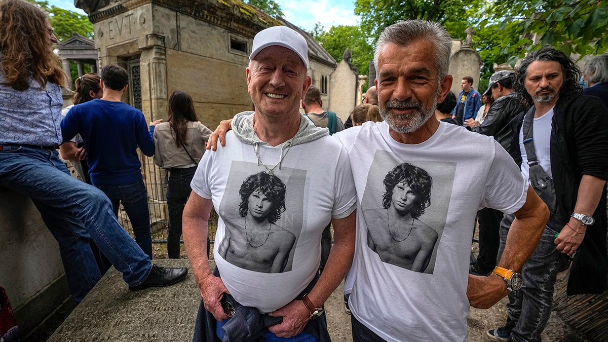 Fred Verheijden, left, and Hans van Schie of the Netherlands wear shirts with a photo of late rock singer Jim Morrison at the Pere-Lachaise cemetery in Paris, Saturday, July 3, 2021. (Associated Press)