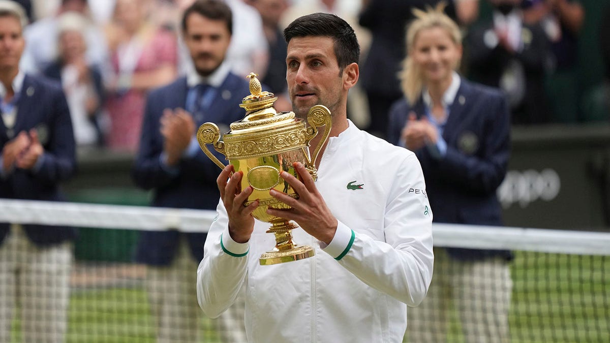 Serbia's Novak Djokovic celebrates holds his winner's trophy and celebrates his victory over Italy's Matteo Berrettini during the men's singles final match on day thirteen of the Wimbledon Tennis Championships in London, Sunday, July 11, 2021. (AP Photo/Alberto Pezzali)